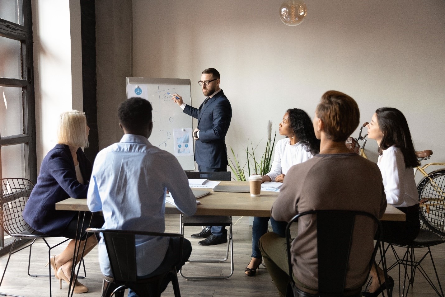 Team meeting in a modern office. Presentation on whiteboard with graphs. PMIS training elevates project management skills and maximizes return on investment.